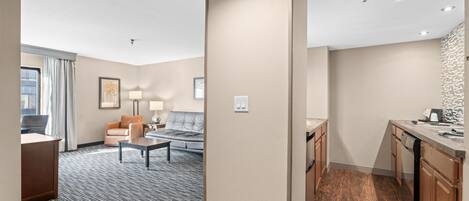A hotel room with a living area, a kitchenette, and a bathroom.