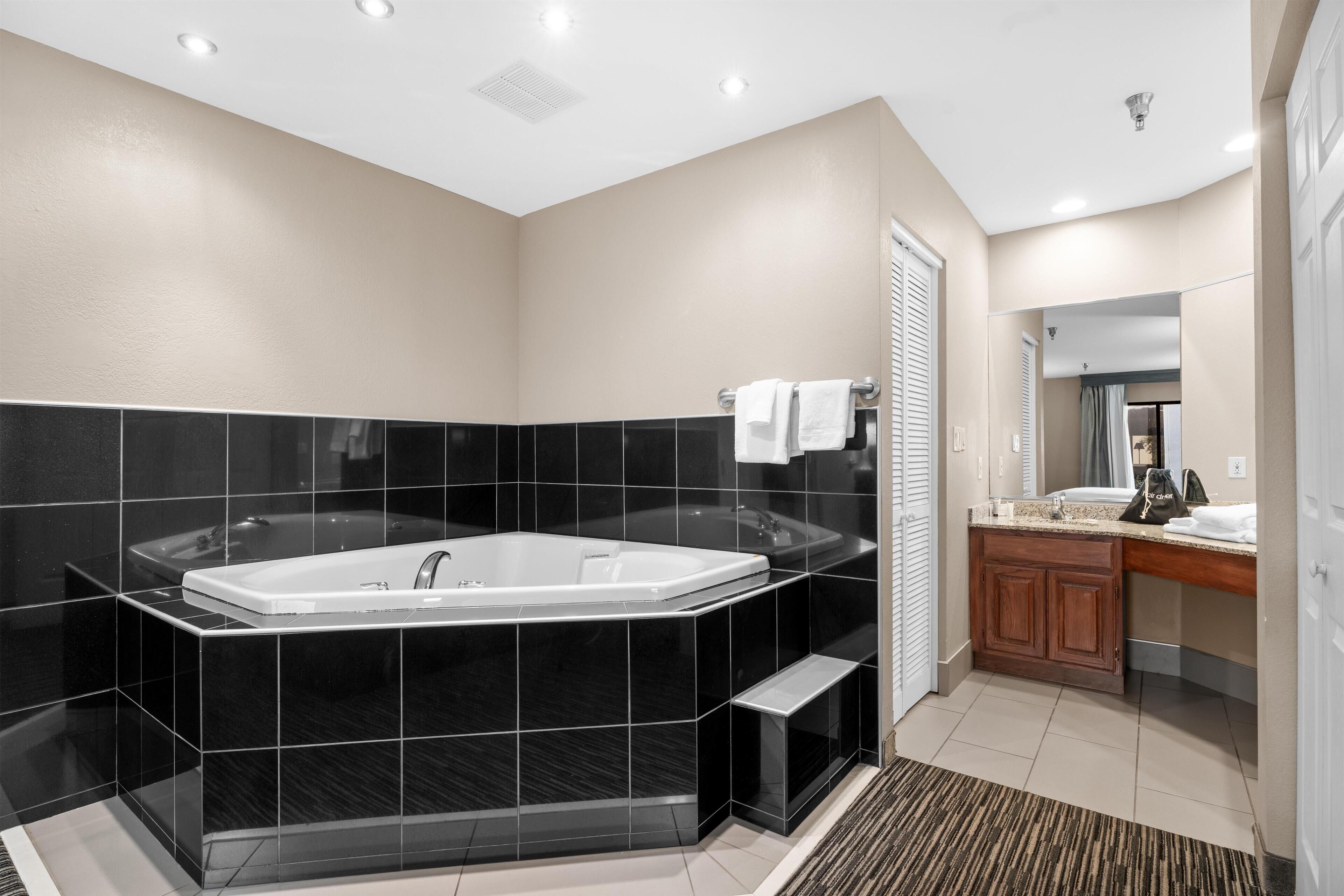 Une salle de bain moderne avec une grande baignoire noire, un espace douche séparé et un meuble-lavabo avec un miroir.