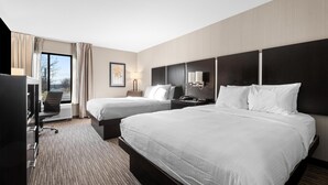 A hotel room with two beds, a desk, a chair, a TV, and a window with curtains.