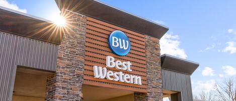 Letrero de un hotel Best Western con un logotipo azul y el nombre 'Best Western' en letras blancas sobre un muro de ladrillo.