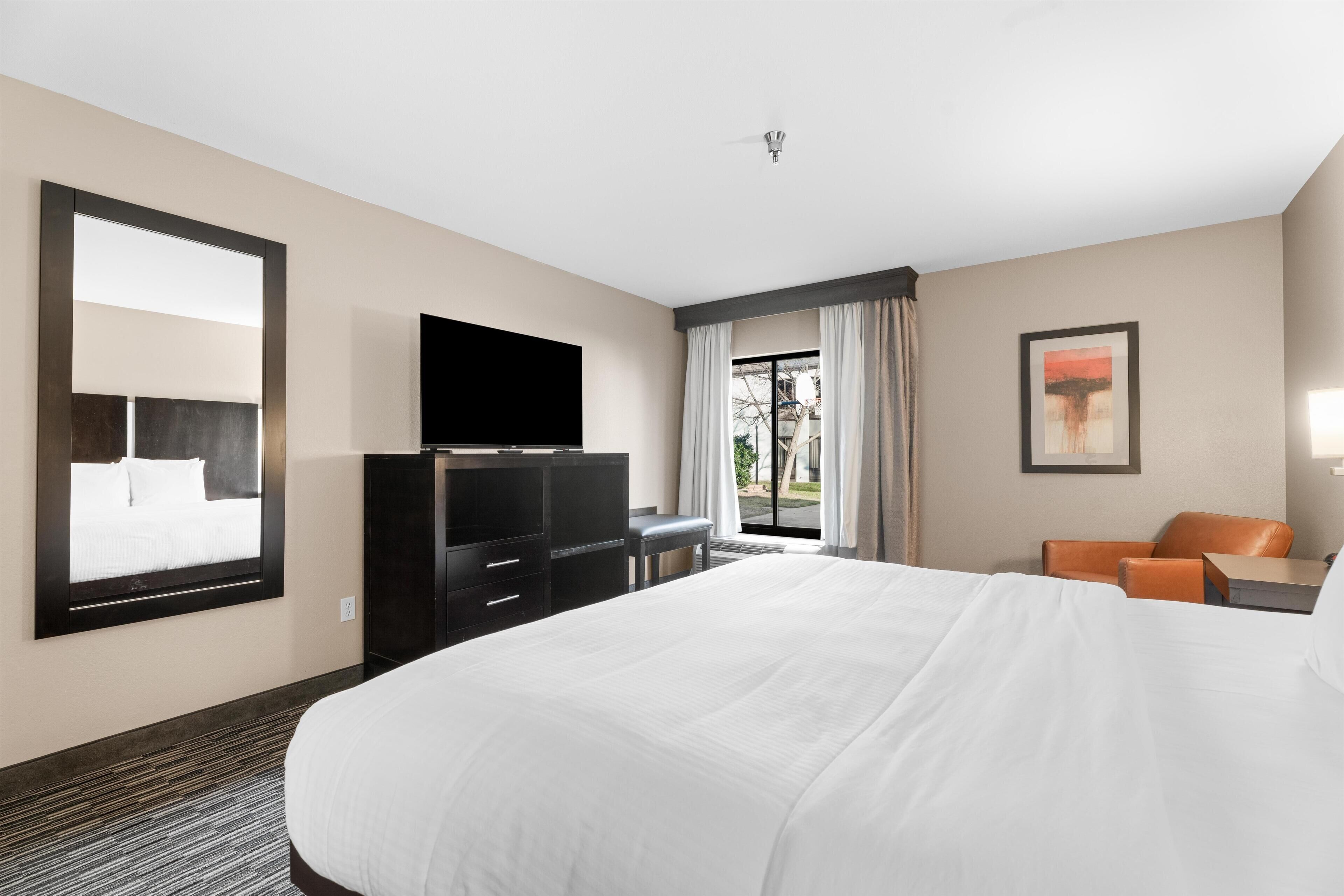 Una camera d'albergo con un letto grande, una TV a schermo piatto, una scrivania e una sedia.