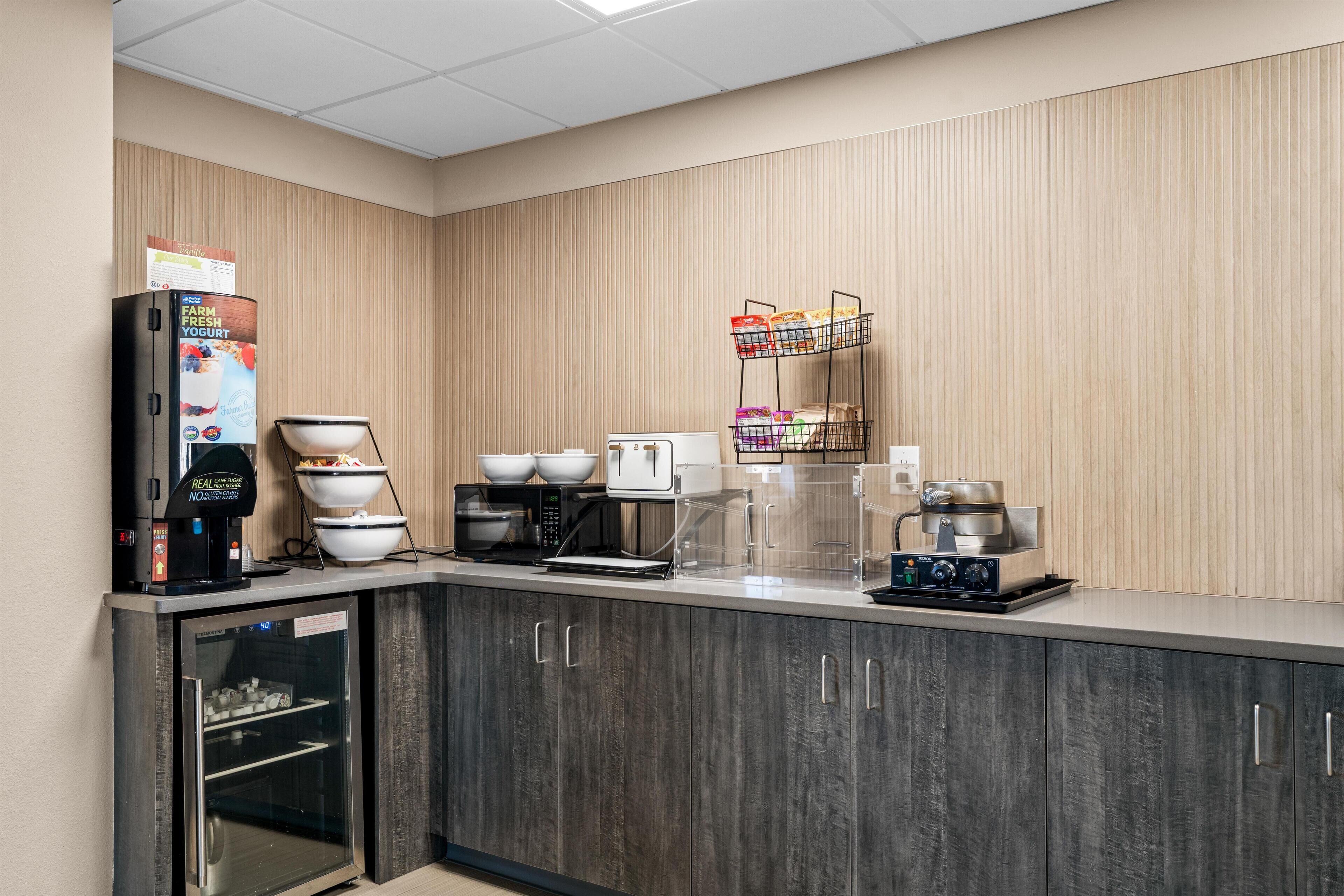 A kitchenette with a coffee maker, microwave, toaster, and a refrigerator.