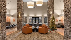 A lobby with stone walls, leather sofas, a Christmas tree, and a dining area.