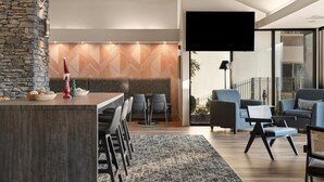 A modern living area with a stone accent wall, a wooden herringbone pattern wall, a flat-screen TV, and a seating area with sofas and chairs.