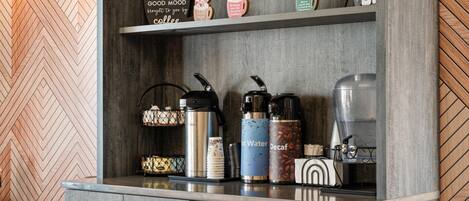 A kitchen area with a coffee station, including a coffee maker, water dispenser, and decaf coffee container.