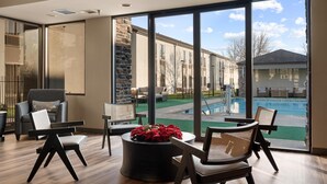 A modern indoor space with a pool view, featuring a stone accent wall, contemporary furniture, and a large window.