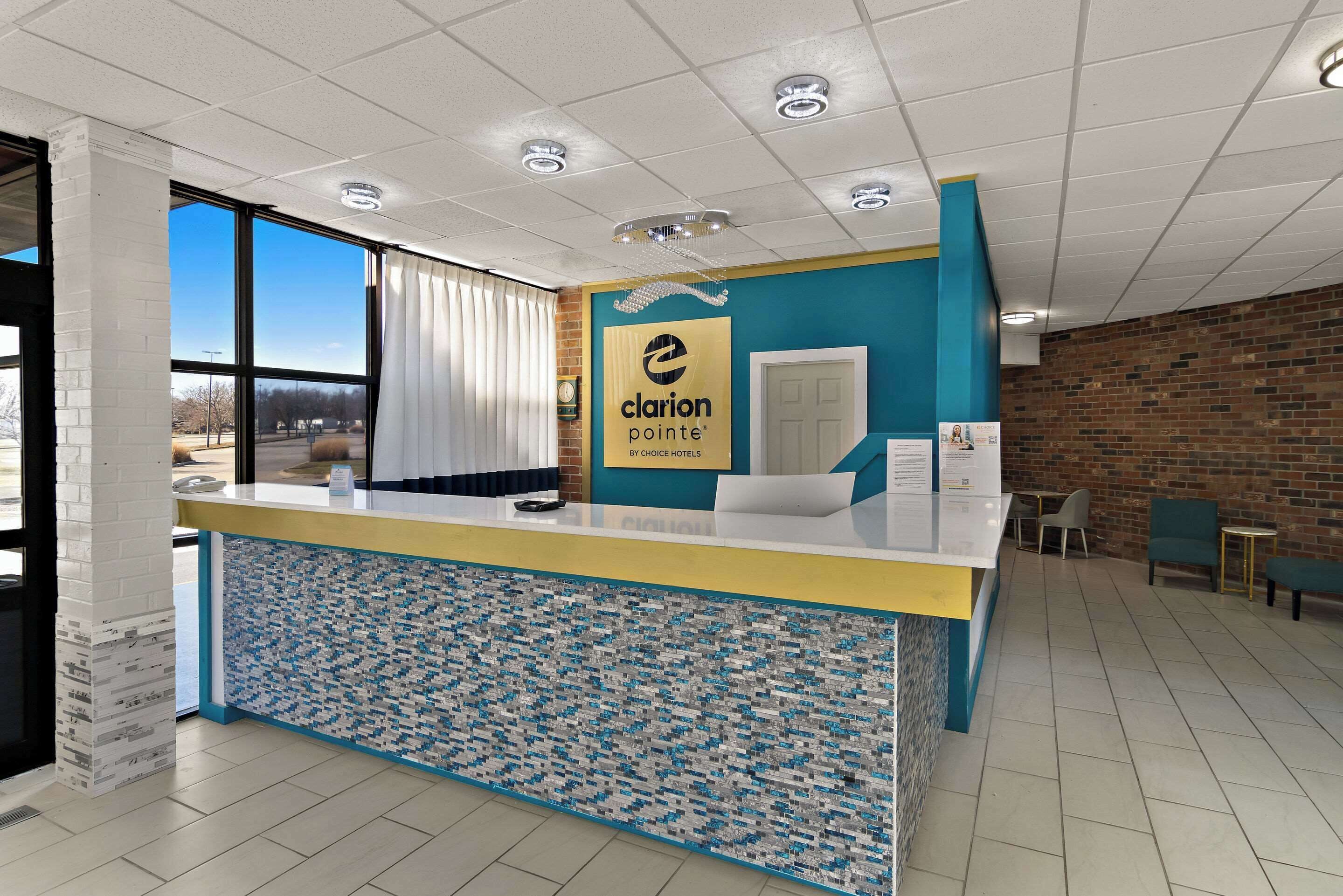 A hotel reception area with a clear view of the outside, a reception desk, and a brick wall.