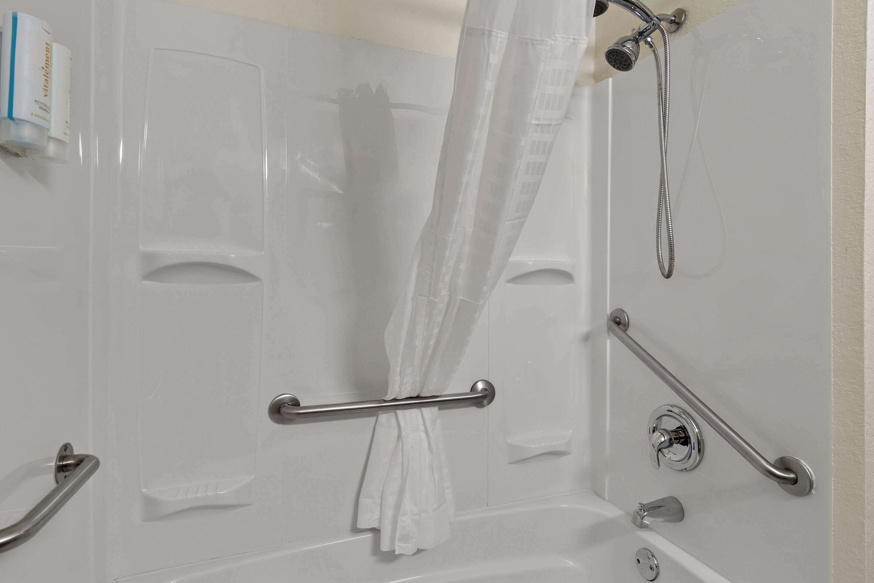 Une salle de bain équipée d’une baignoire, d’une douche et d’une barre d’appui.