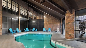 Una piscina interior con sillas azules y una pared de ladrillo.