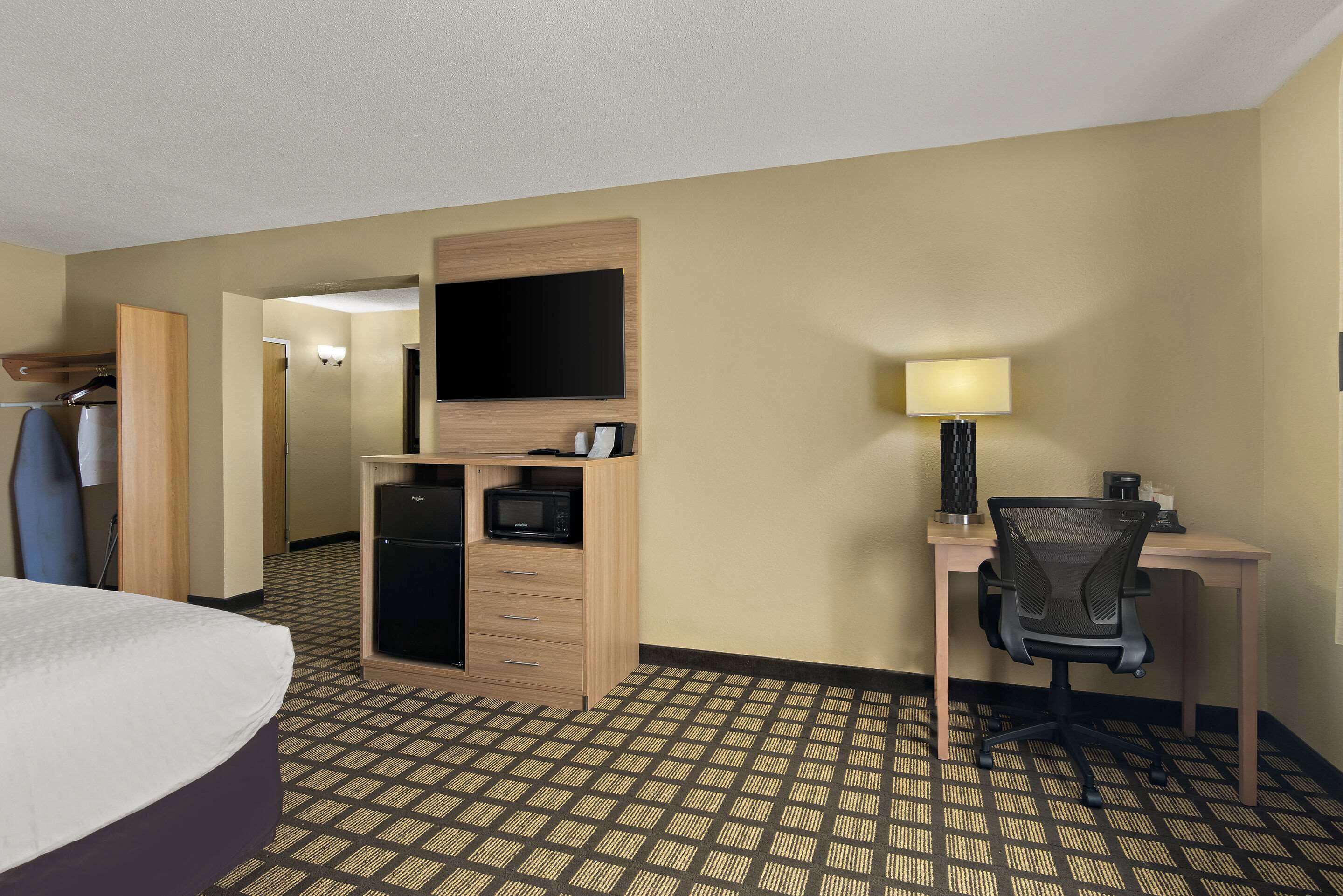 Habitación de hotel con cama, escritorio con silla, televisión, microondas y armario.