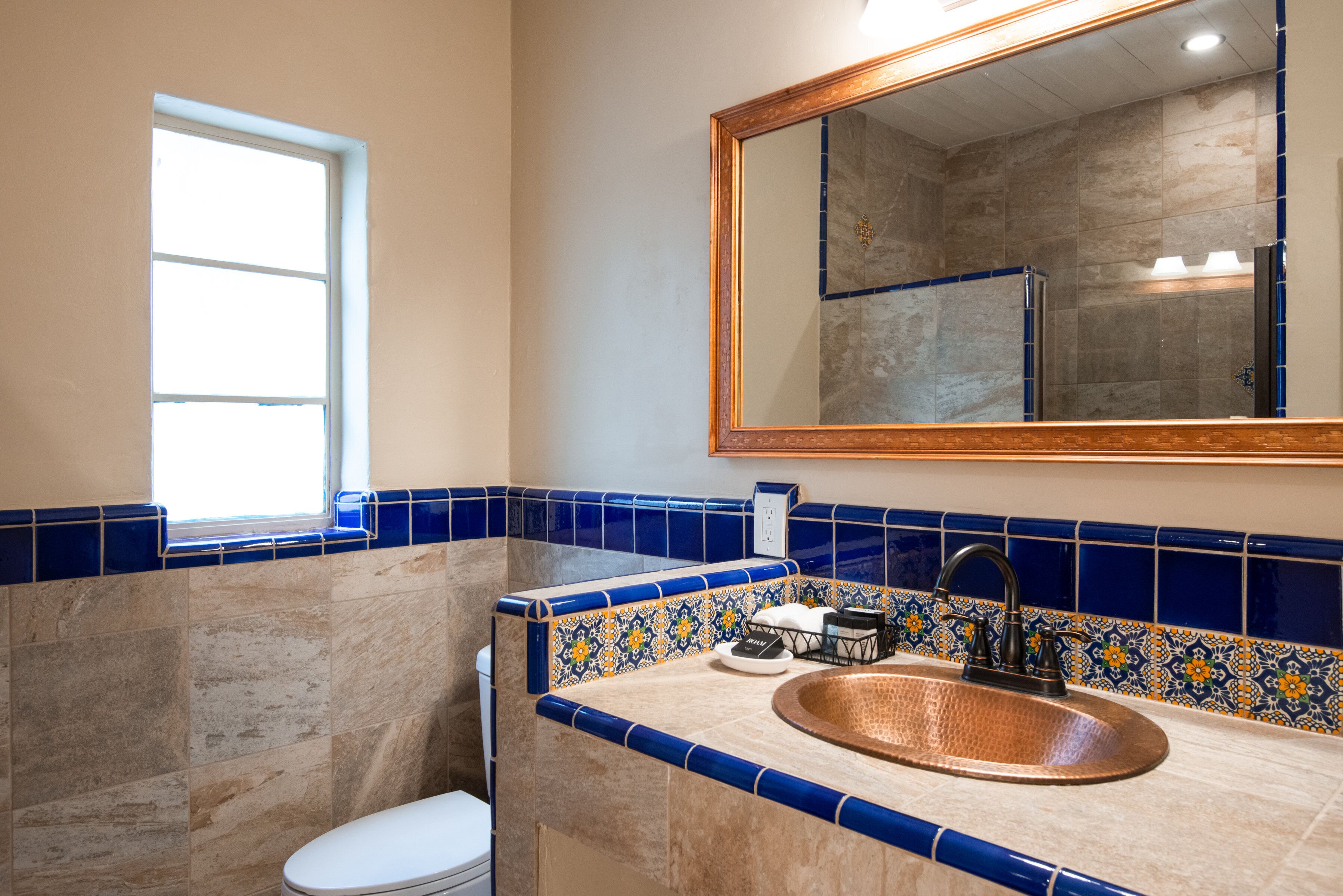 A bathroom with a large mirror, a sink, and a window.