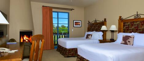 A hotel room with two beds, a desk, a chair, a fireplace, and a view of the outdoors.