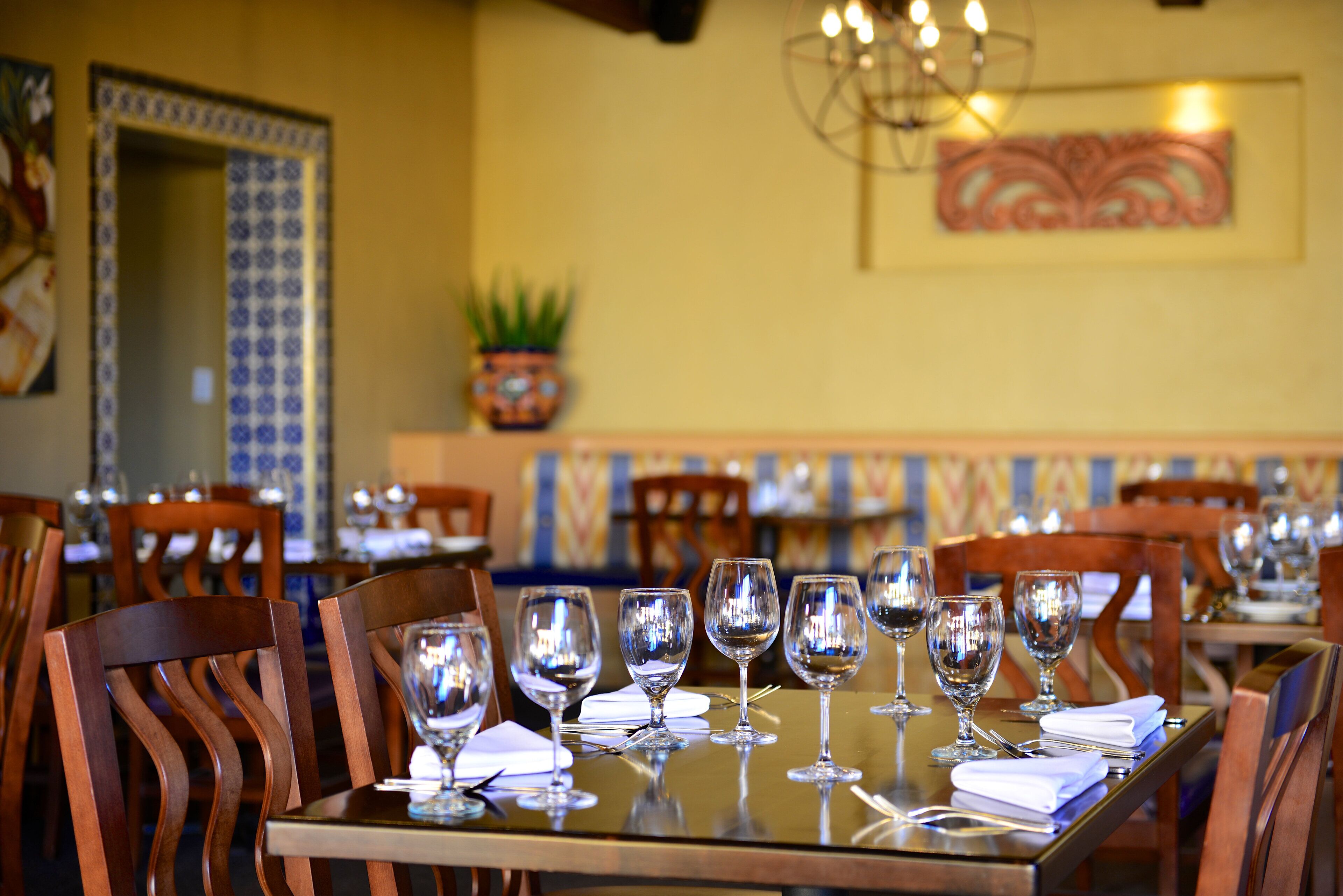 A dining area with tables set for a meal, chairs, and a decorative wall.
