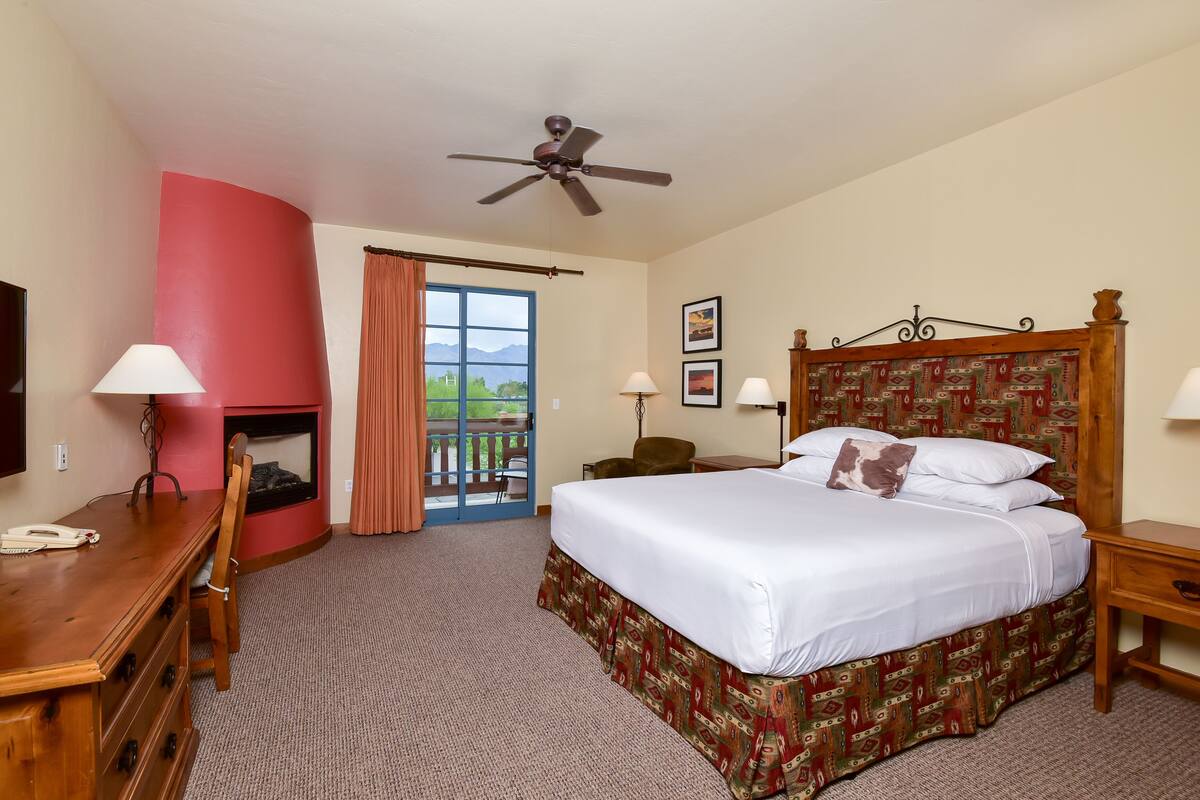 Une chambre d’hôtel avec un lit, un bureau, une chaise et une cheminée.