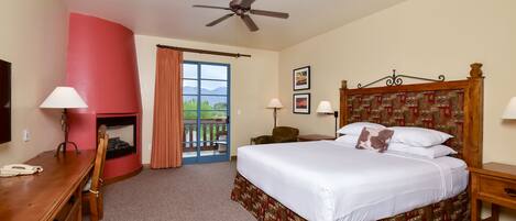 A hotel room with a bed, desk, chair, and a fireplace.