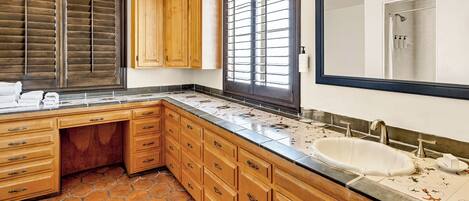 A bathroom with a large mirror, a sink, and wooden cabinets.
