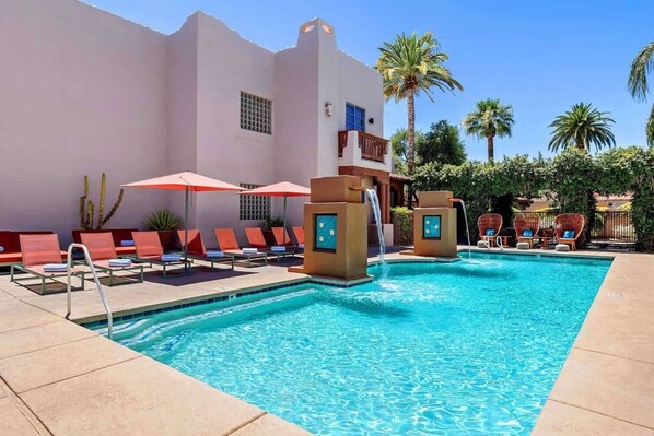 Relax by the clear blue pool surrounded by lounge chairs and umbrellas.