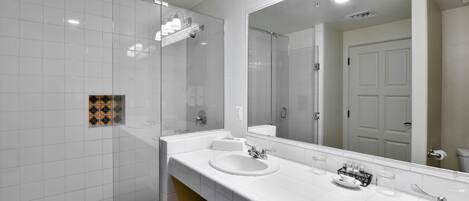 A modern bathroom with two sinks, a large mirror, and a shower area.