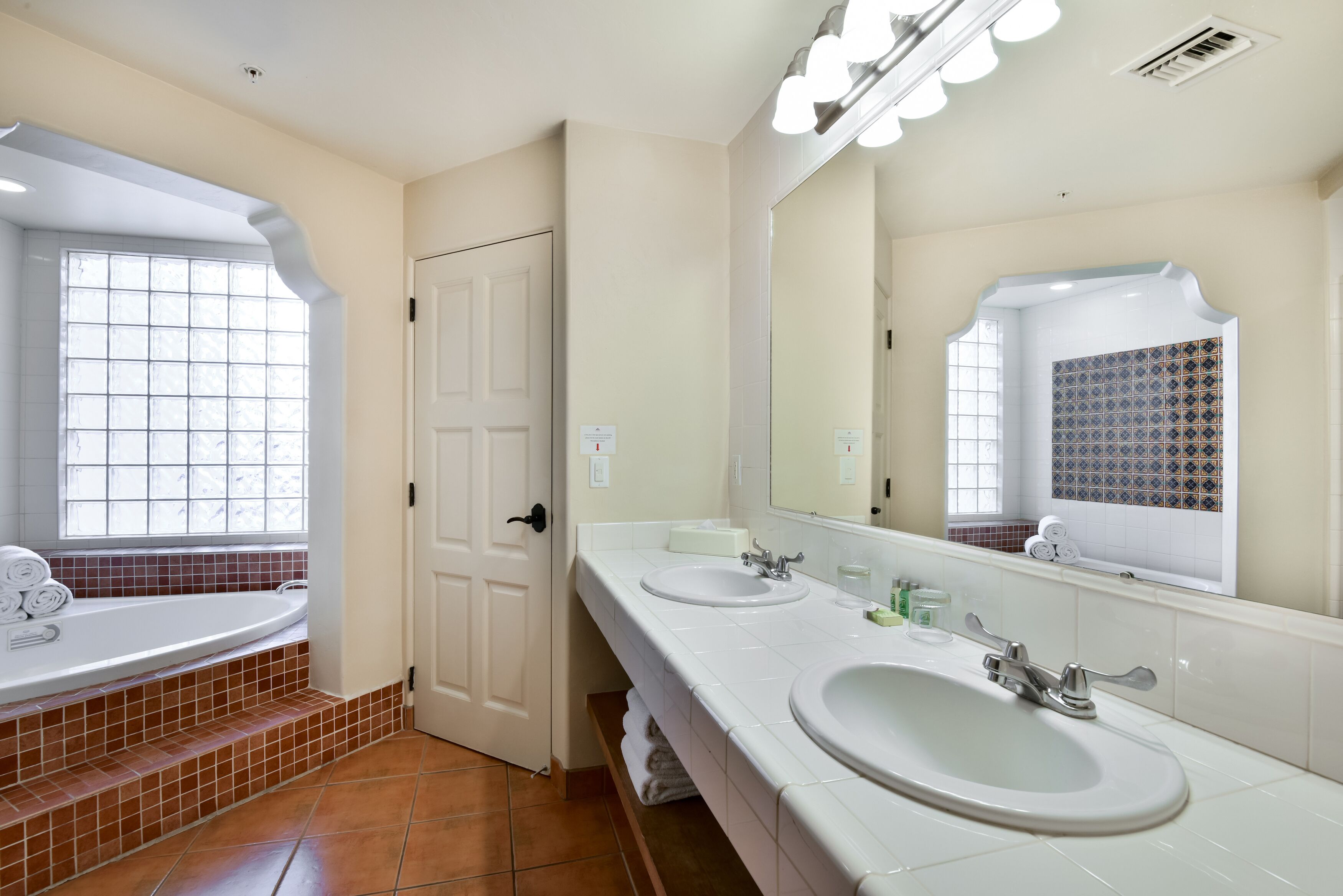 Une salle de bain avec deux lavabos, un grand miroir et une fenêtre donnant sur un beau paysage.