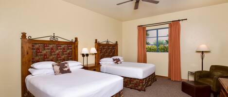 A hotel room with two single beds, a ceiling fan, a window with curtains, a lamp, and a chair.