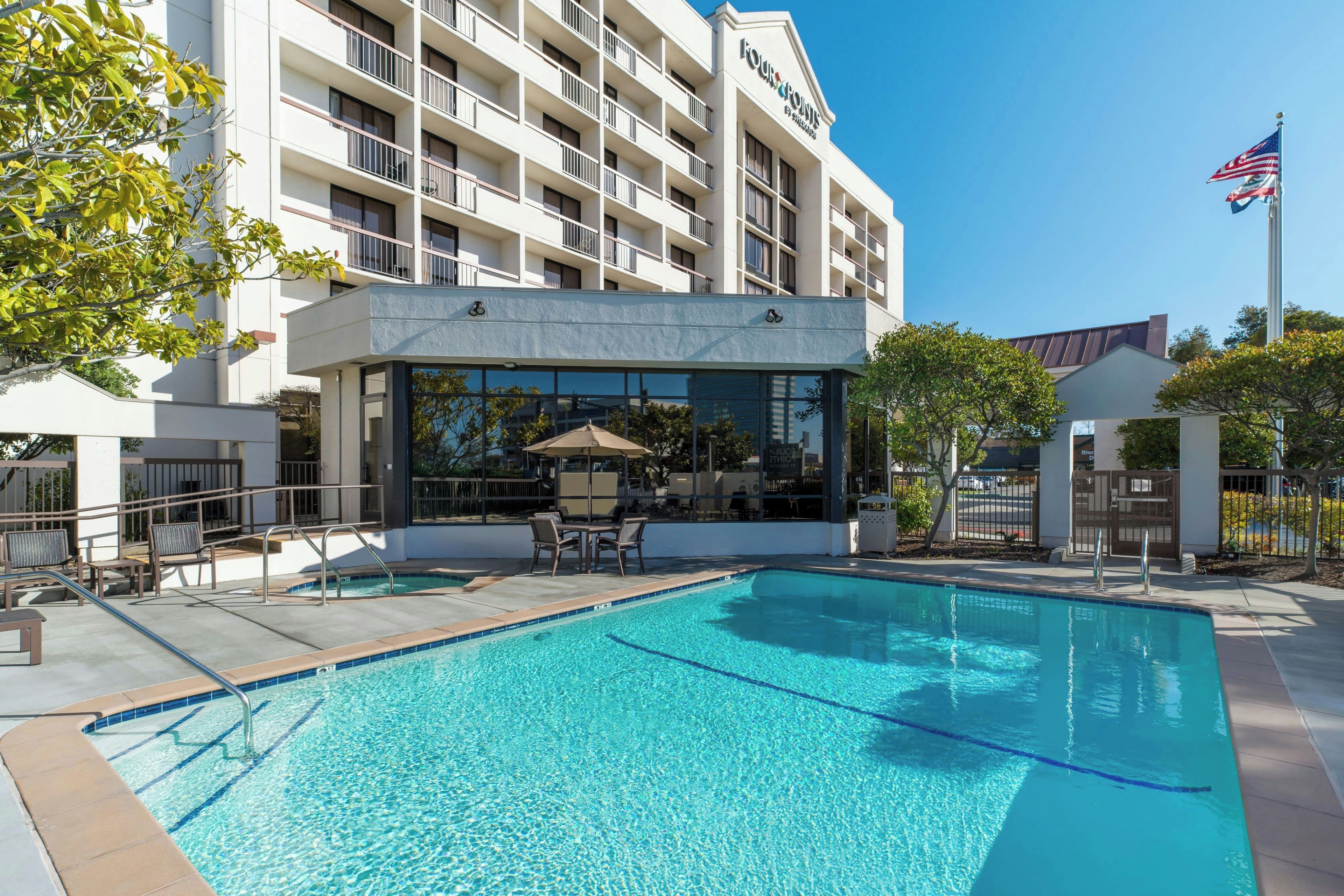 Un hotel con piscina, asientos al aire libre y un cielo azul despejado.