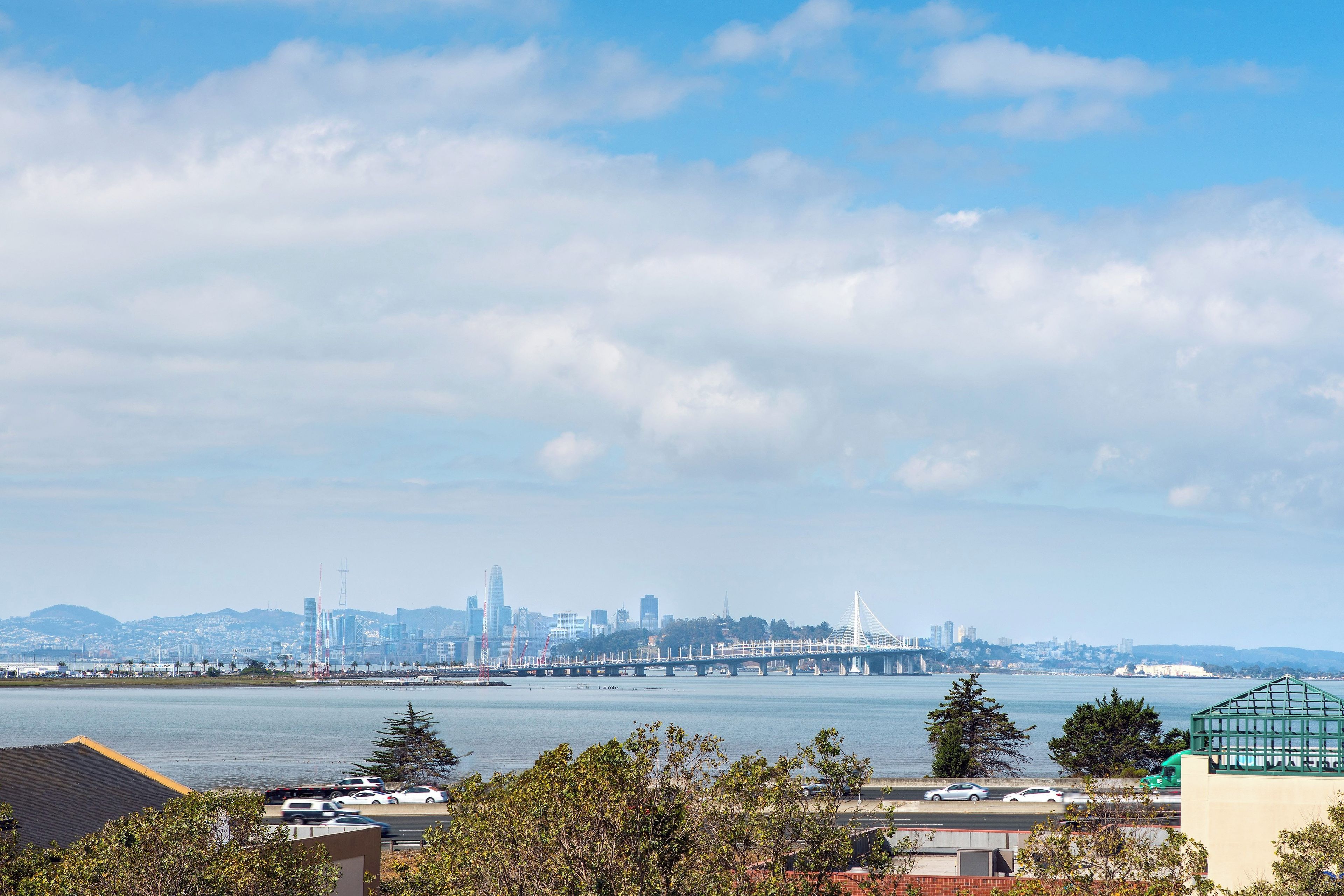 Une vue sur les gratte-ciel d’une ville, avec un pont imposant et une étendue d’eau au premier plan.
