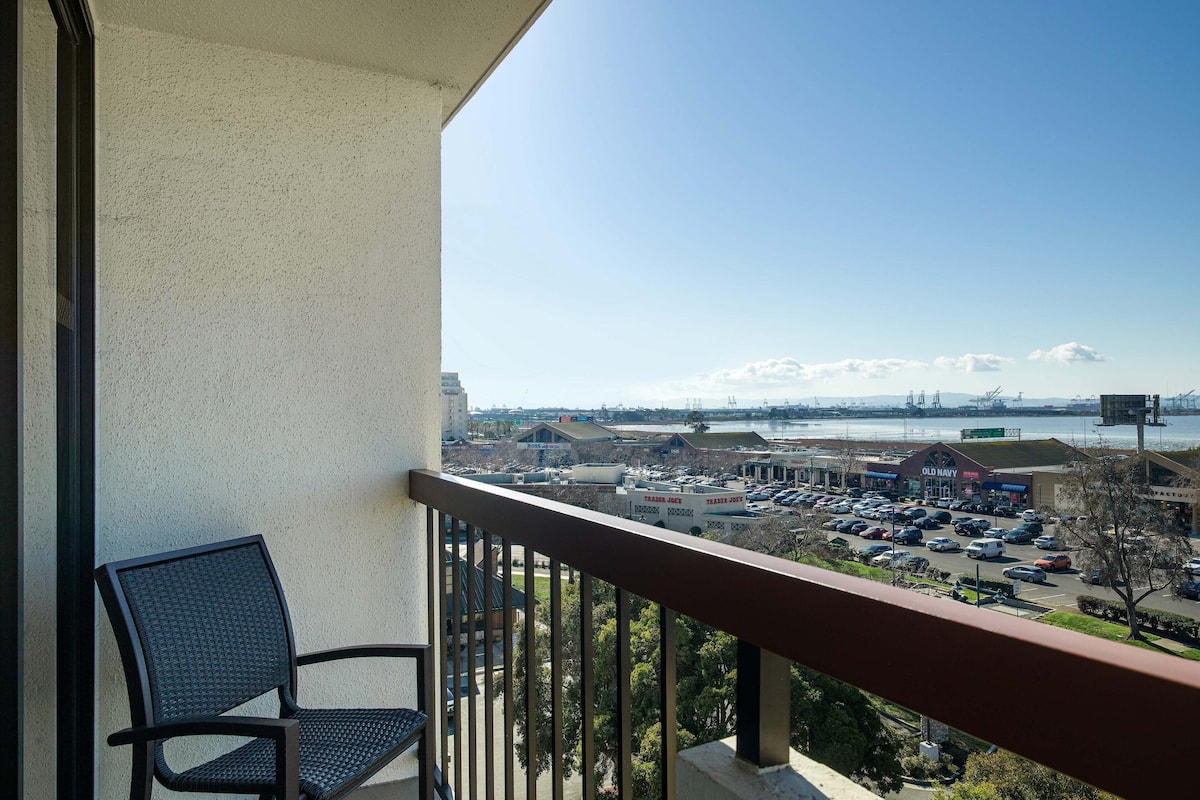 Ein Balkon mit Blick auf einen Parkplatz und Gebäude gegenüber dem Wasser.