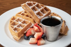 A plate with waffles, strawberries, blueberries, and syrup. - Four Points by Sheraton San Francisco Bay Bridge (Emeryville)