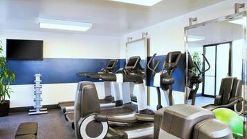 A gym with treadmills, stationary bikes, and exercise balls.