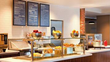 A breakfast buffet area with various food options and a menu board.