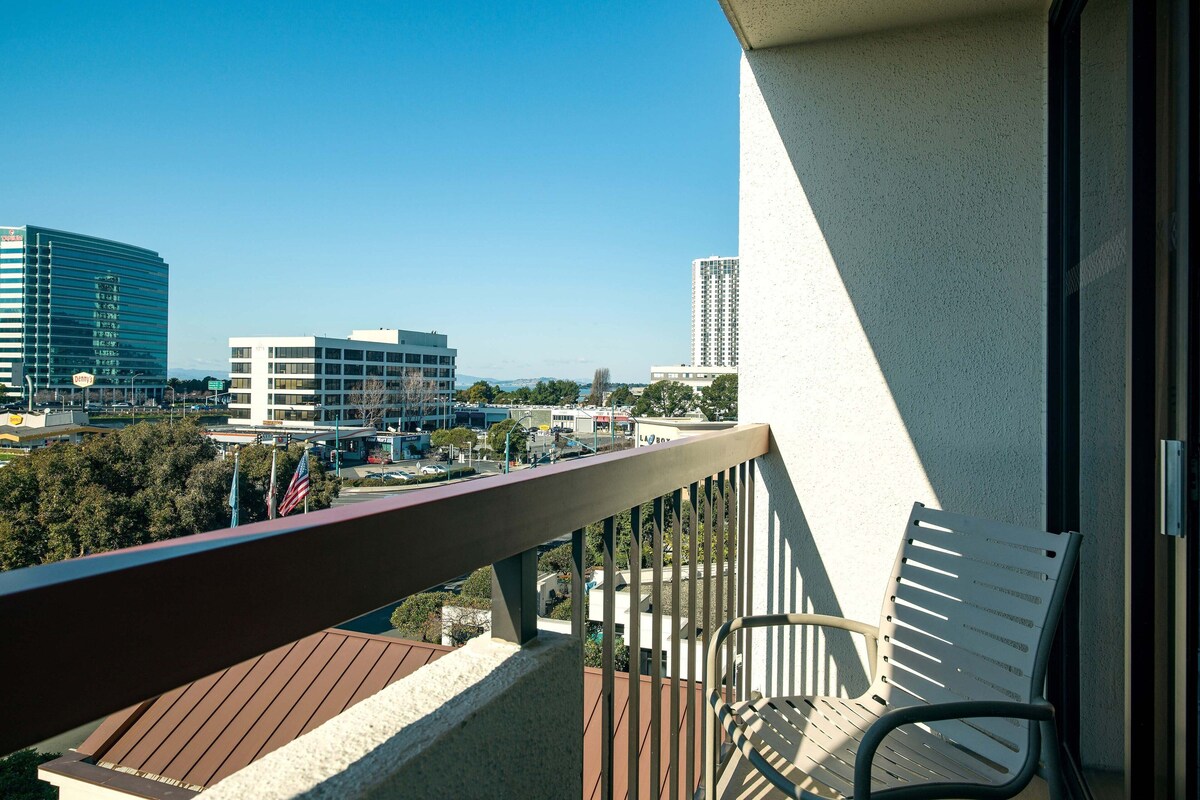 Een balkon met uitzicht op een stadsgezicht, inclusief gebouwen en een heldere lucht.
