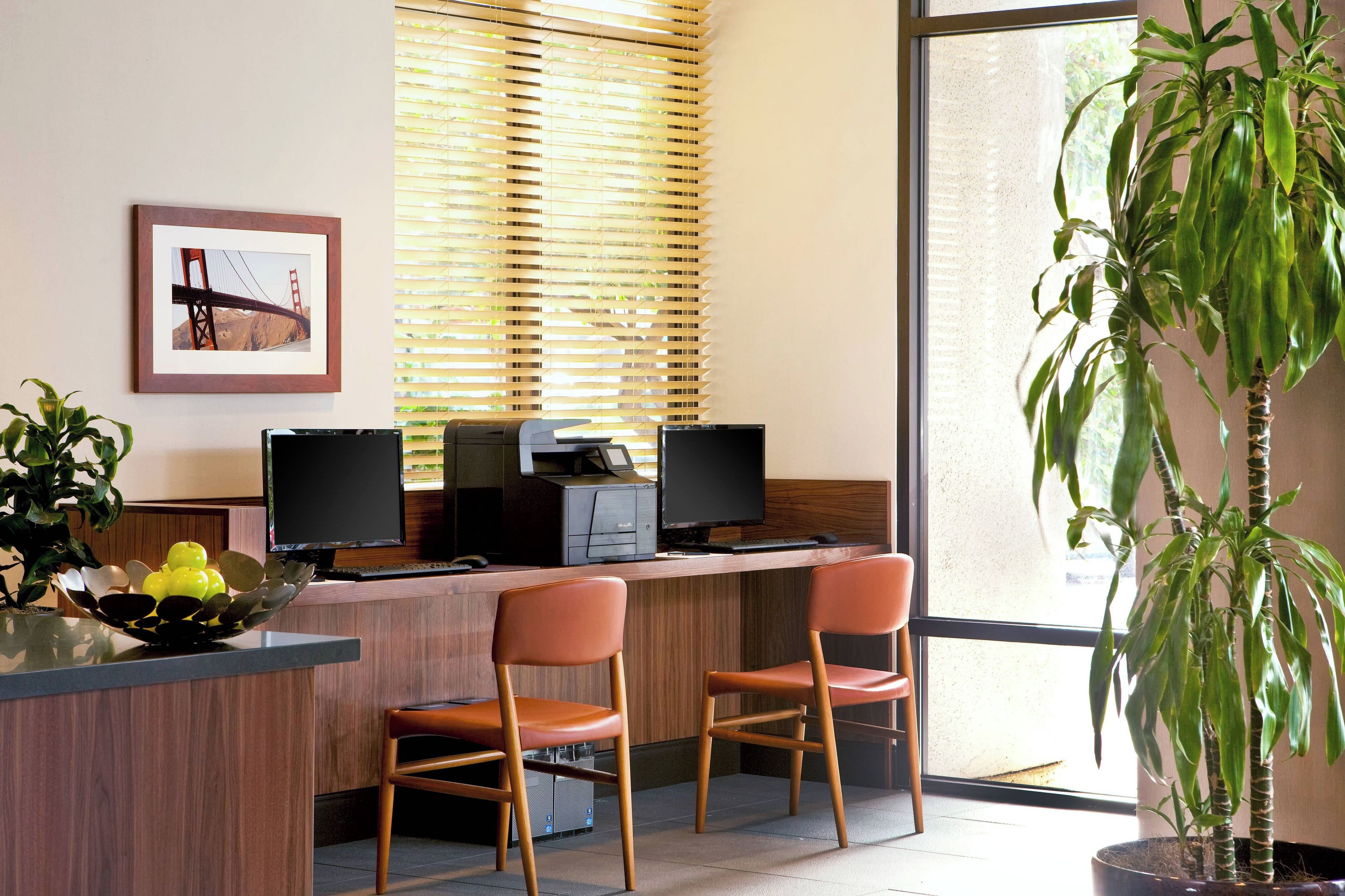 Uma mesa de recepção com duas cadeiras, uma impressora e um monitor.
