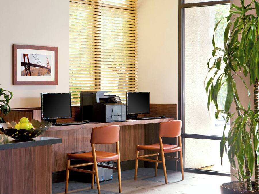 Uma mesa de recepção com duas cadeiras, uma impressora e um monitor.