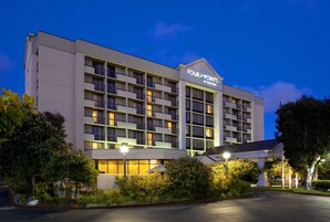 A hotel with multiple floors, balconies, and a well-lit entrance.