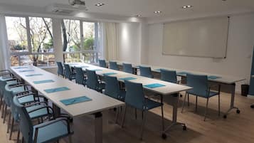 Un salón de conferencias con una larga mesa, sillas azules y una pizarra.