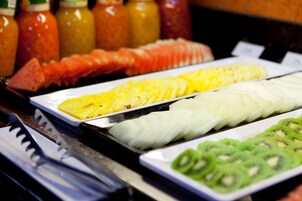 A buffet with various food options including sliced pineapple, white fish, and kiwi.