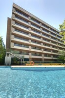 Ein mehrstöckiges Hotel mit Schwimmbad davor.
