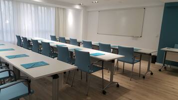 A conference room with a long table, chairs, a whiteboard, and a projector screen.