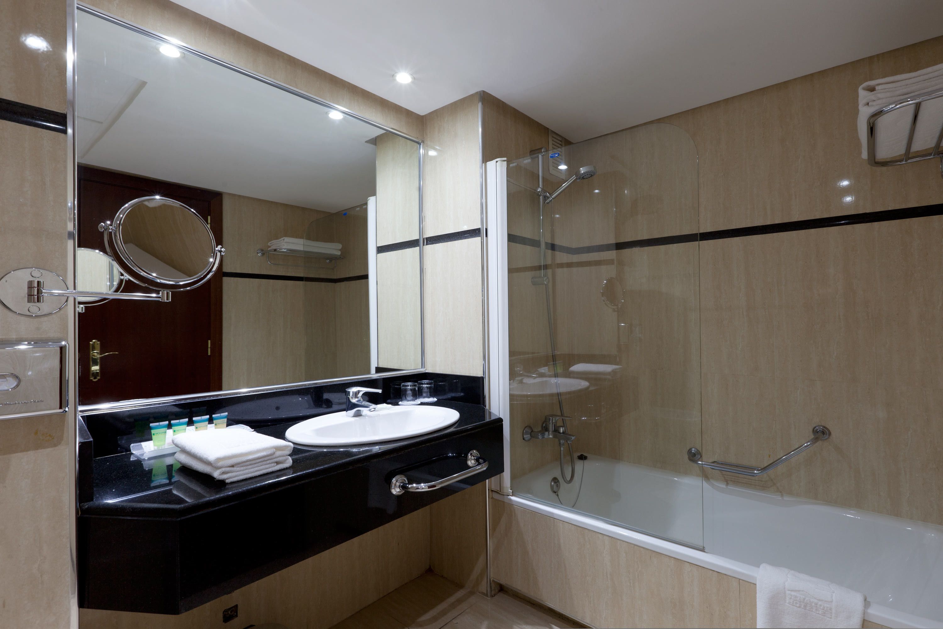 A modern bathroom with a black countertop, white sink, and a glass-enclosed shower.