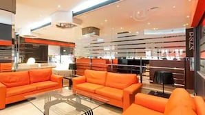 Un intérieur moderne avec des canapés orange, une table basse en verre et un coin bar doté d’un comptoir.