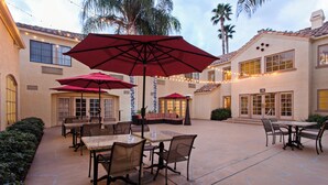 A patio area with outdoor seating, tables, and umbrellas. - Hilton Garden Inn Valencia Six Flags (Valencia)