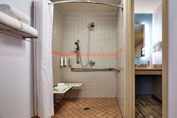 A shower with a handrail, a towel rack, and a small table with a towel.