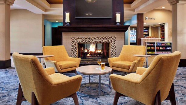 A lobby with a fireplace, seating area, and a store named 'The Shop'. - Hilton Garden Inn Valencia Six Flags (Valencia)