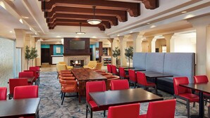 A hotel lobby with a fireplace, multiple seating areas, and a reception desk. - Hilton Garden Inn Valencia Six Flags (Valencia)