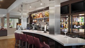 A modern bar area with a curved counter, bar stools, a digital menu display, and a well-stocked liquor shelf. - Courtyard by Marriott Fishkill (Fishkill)