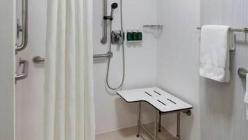 A bathroom with a shower, grab bars, a bench, and a towel rack.