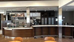 A modern bar area with a curved counter, seating, and a coffee machine. - Courtyard by Marriott Fishkill (Fishkill)