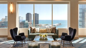 A modern hotel room with a large window offering a cityscape view, a green sofa, two armchairs, and a coffee table with flowers. - Swissotel - Chicago (Chicago)
