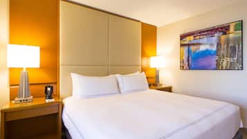 Habitación de hotel con una cama grande, dos mesitas de noche con lámparas, un teléfono y un cuadro en la pared.
