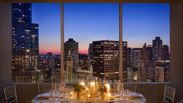 A dining table set for six with a cityscape view through large windows. - Swissotel - Chicago (Chicago)